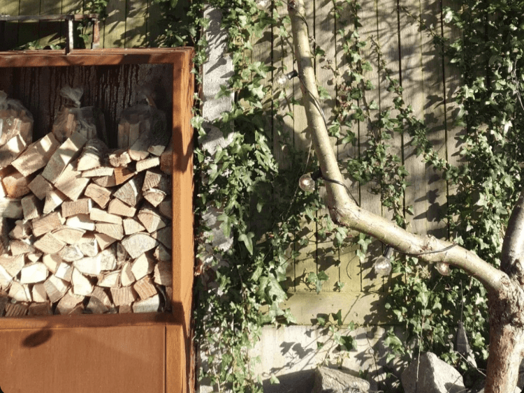 Detailansicht eines Brennholzregals aus Cortenstahl mit gestapeltem Kaminholz