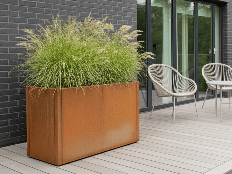 Pflanzkasten aus Cortenstahl von CUBY mit dichter Bepflanzung auf Holzterrasse