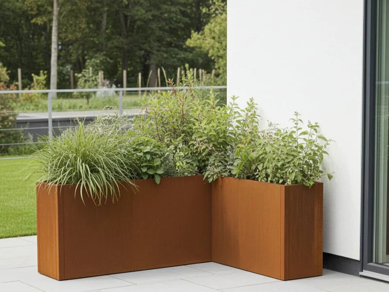CUBY Eckpflanzkasten aus Cortenstahl mit Ziergräsern und Sträuchern am Haus