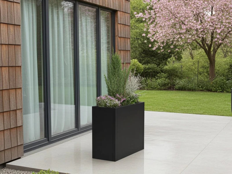 Minimalistischer Pflanzkasten aus schwarzem Stahl vor modernem Haus