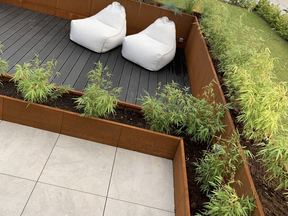 byJEMA Pflanzkübel aus Cortenstahl integriert in eine Terrasse mit Sitzbereich