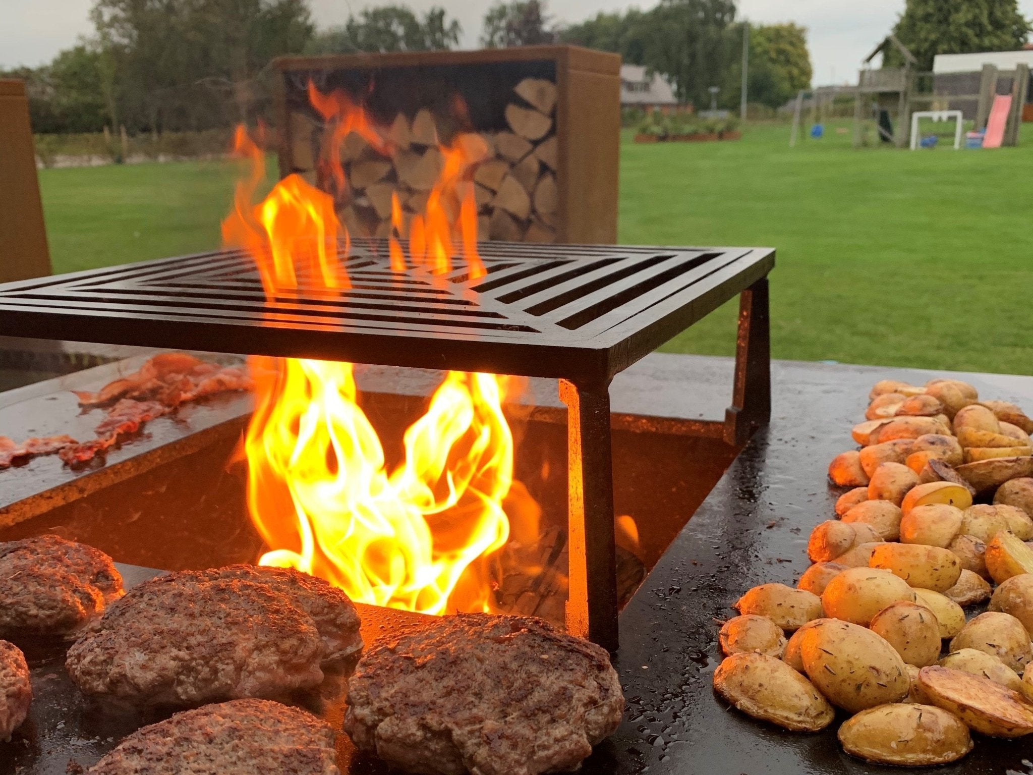 byJEMA Feuerstelle aus Cortenstahl mit Grillplatte – saftige Burger und Brioche-Brötchen über offenem Feuer