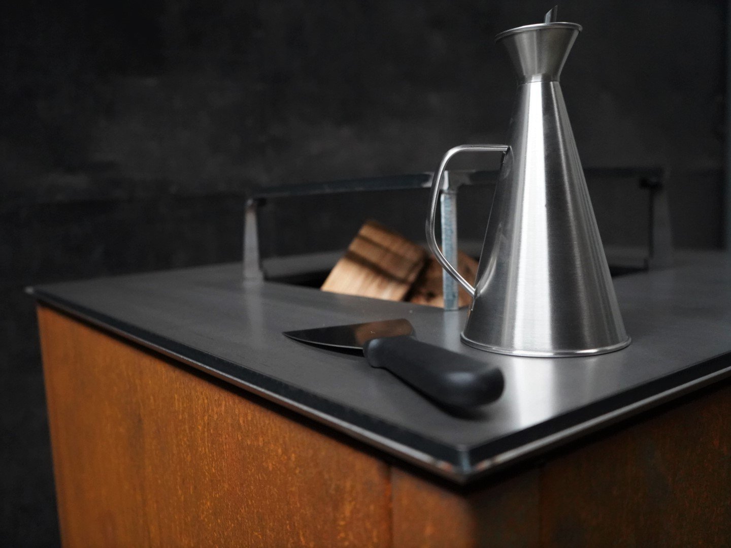 Detailaufnahme der byJEMA Feuerstelle aus Cortenstahl mit schwarzer Stahlplatte und massivem Grillrost