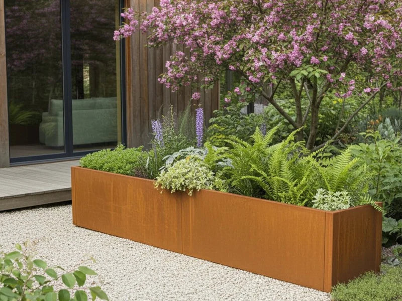 CUBY Pflanzkasten aus Cortenstahl mit blühender Bepflanzung unter Zierbaum