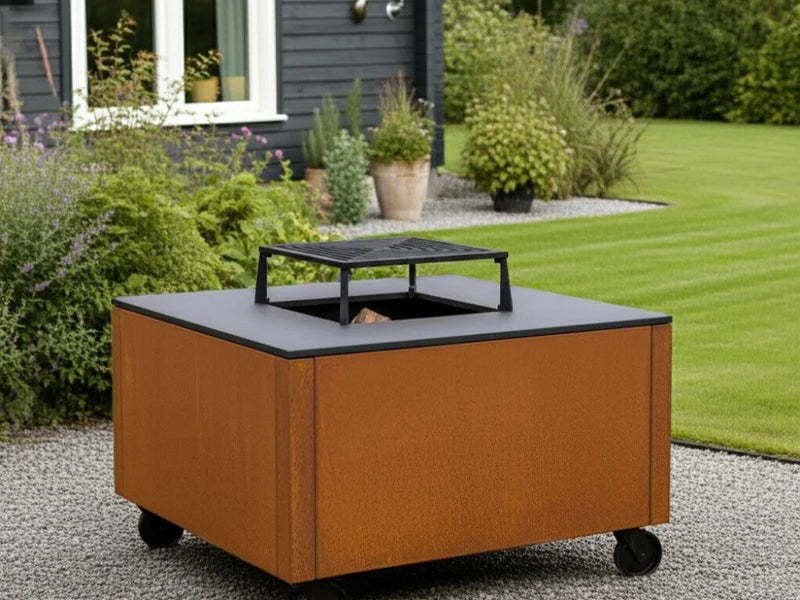 CUBY Feuergrill aus Cortenstahl im klassischen Garten mit Rasen und Sträuchern