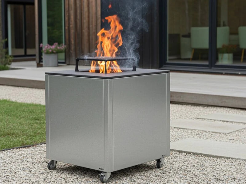 CUBY Feuergrill aus verzinktem Stahl auf Terrasse am Haus mit Pflanzen und sichtbaren Flammen