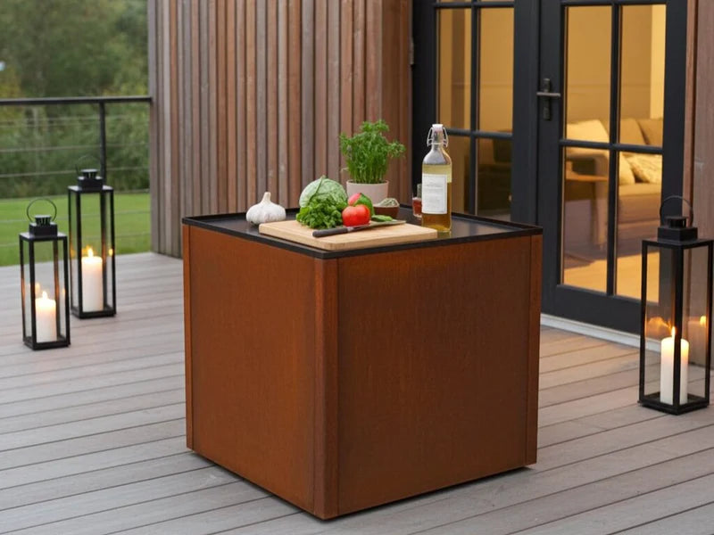 CUBY Outdoor-Küchentisch aus Cortenstahl auf Holzterrasse mit Laternen