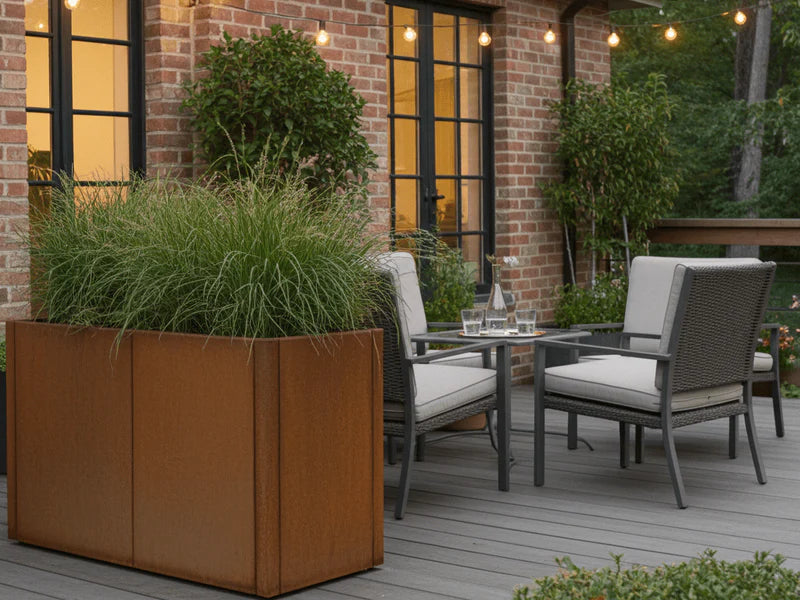 Großer Pflanzkasten aus Cortenstahl von CUBY neben Sitzbereich auf Holzterrasse