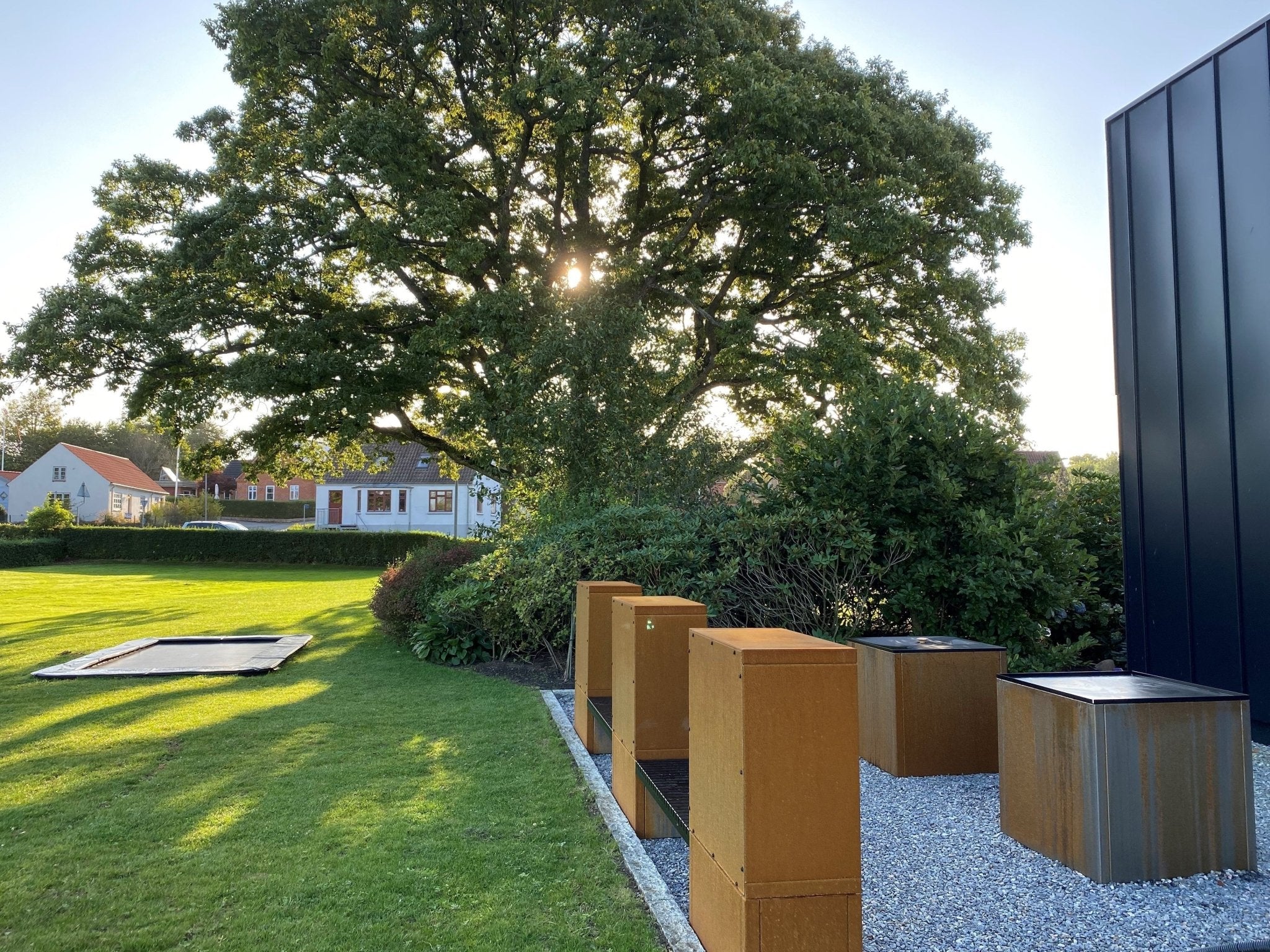Holzregal aus Cortenstahl mit Sitzbank auf moderner Terrasse im Garten