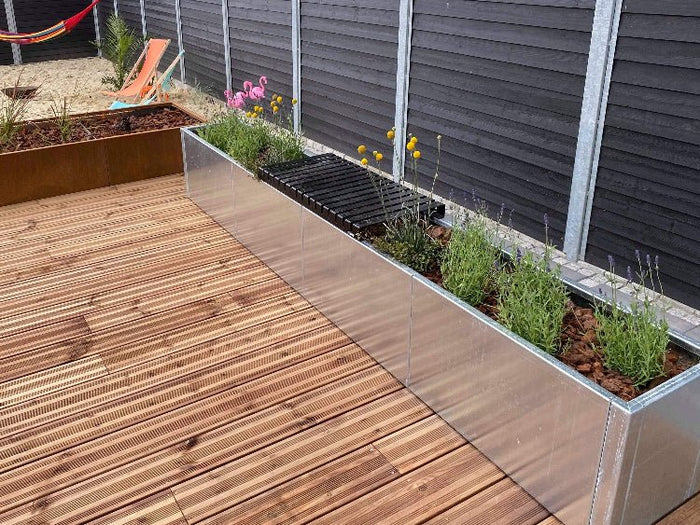 Langer Pflanzkübel aus verzinktem Stahl entlang einer Holzterrasse